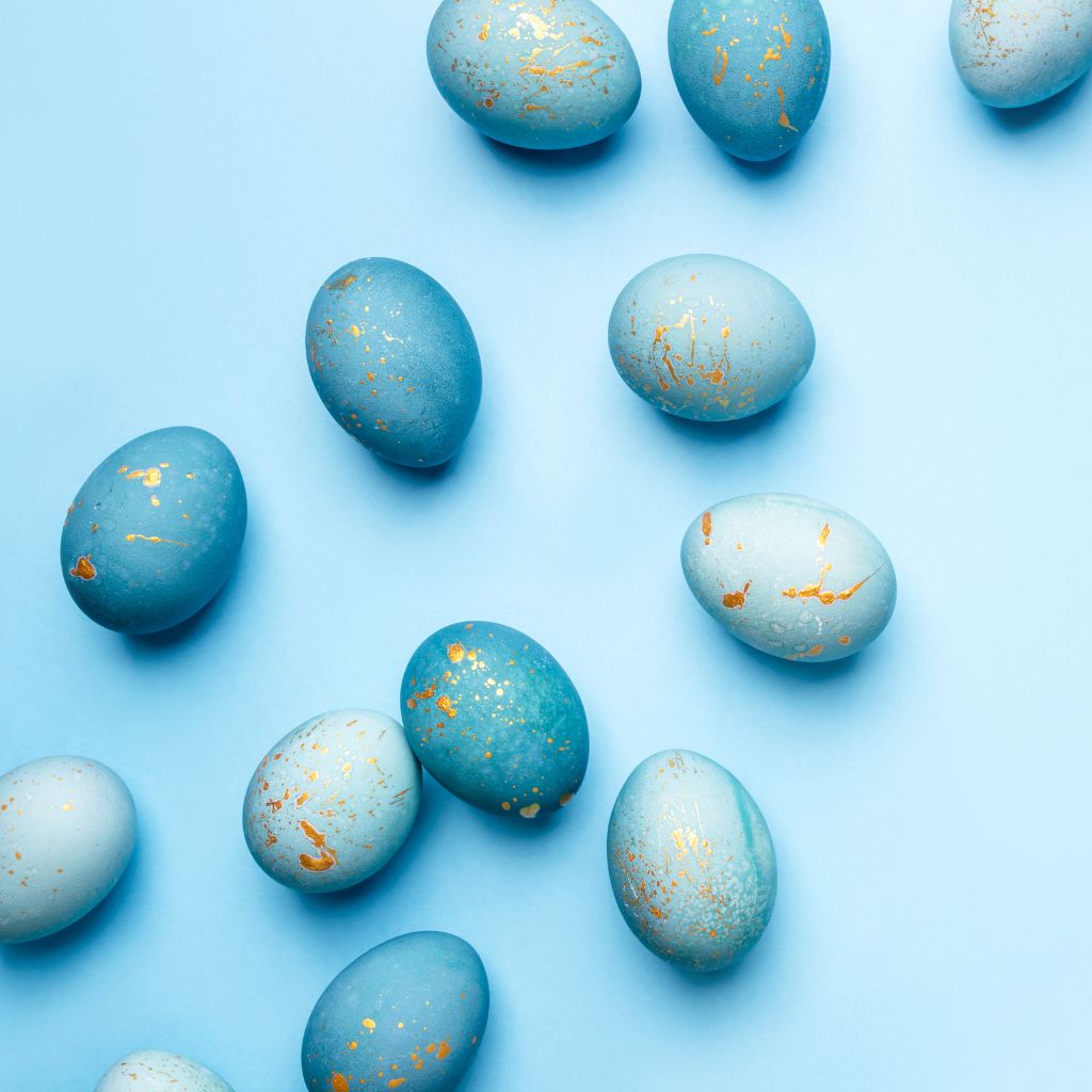 Shiny gold-foiled Easter eggs displayed against a blue backdrop, representing Easter activities in the DFW area.