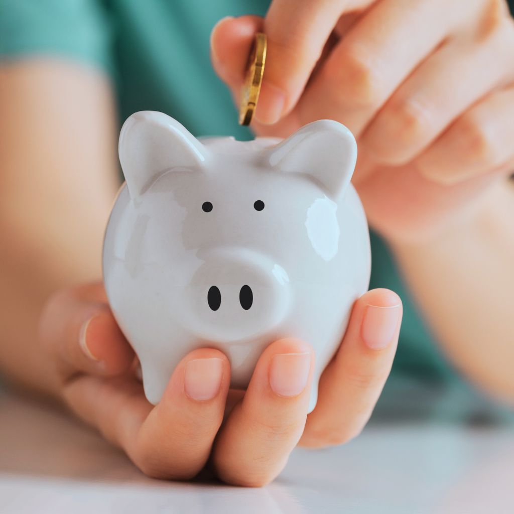 A person inserting a coin into a piggy bank, symbolizing savings during the Tax Free Weekend in Dallas Fort Worth.
