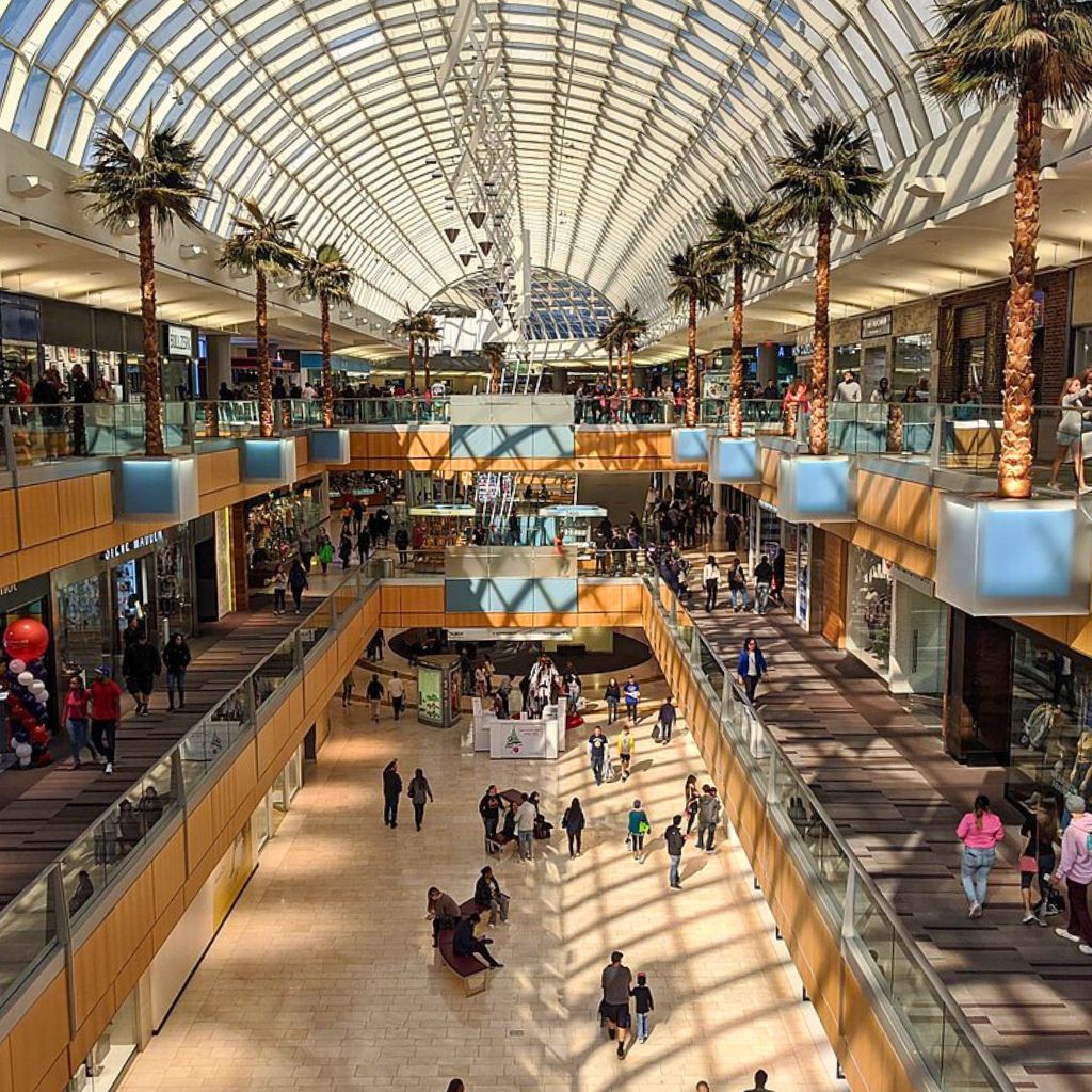A vibrant indoor mall scene with many visitors, featuring Galleria Dallas as a popular August destination for families.