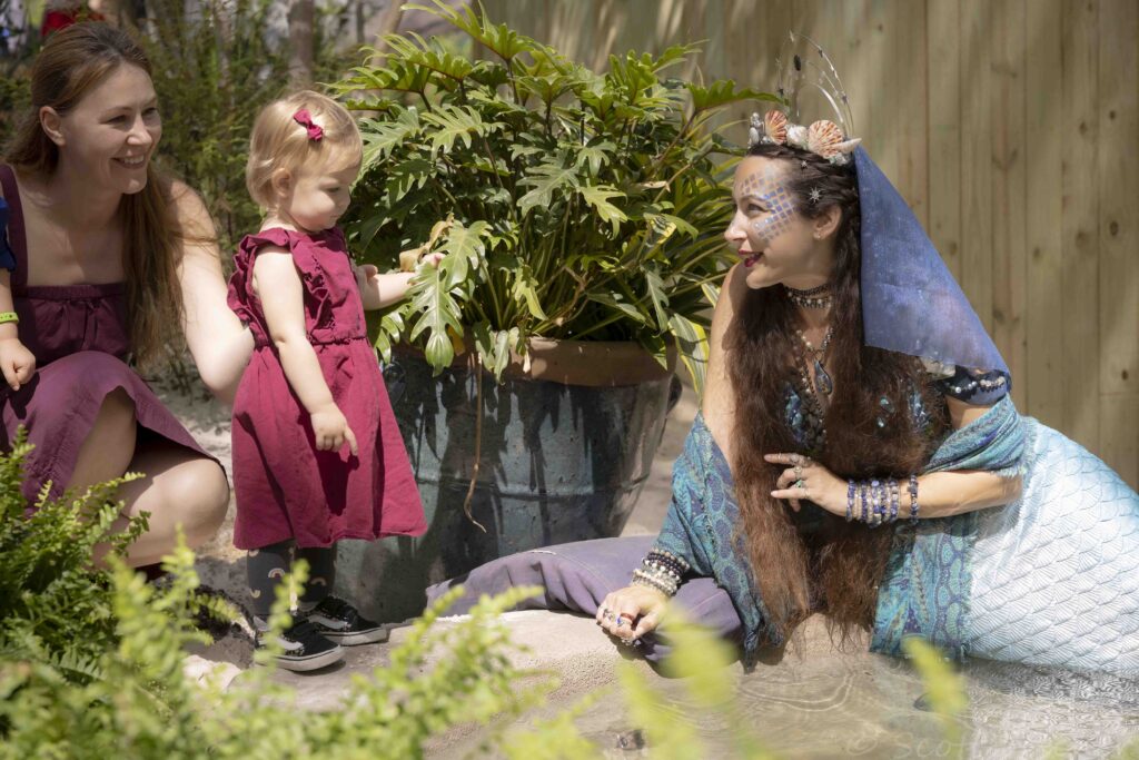 Child meeting a mermaid performer at Scarborough Renaissance Festival 2026 in Waxahachie Texas